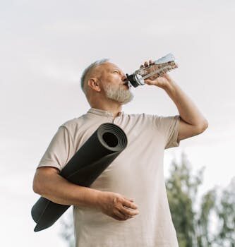 Elderly man drinking water while holding a yoga mat outdoors, promoting fitness and hydration.